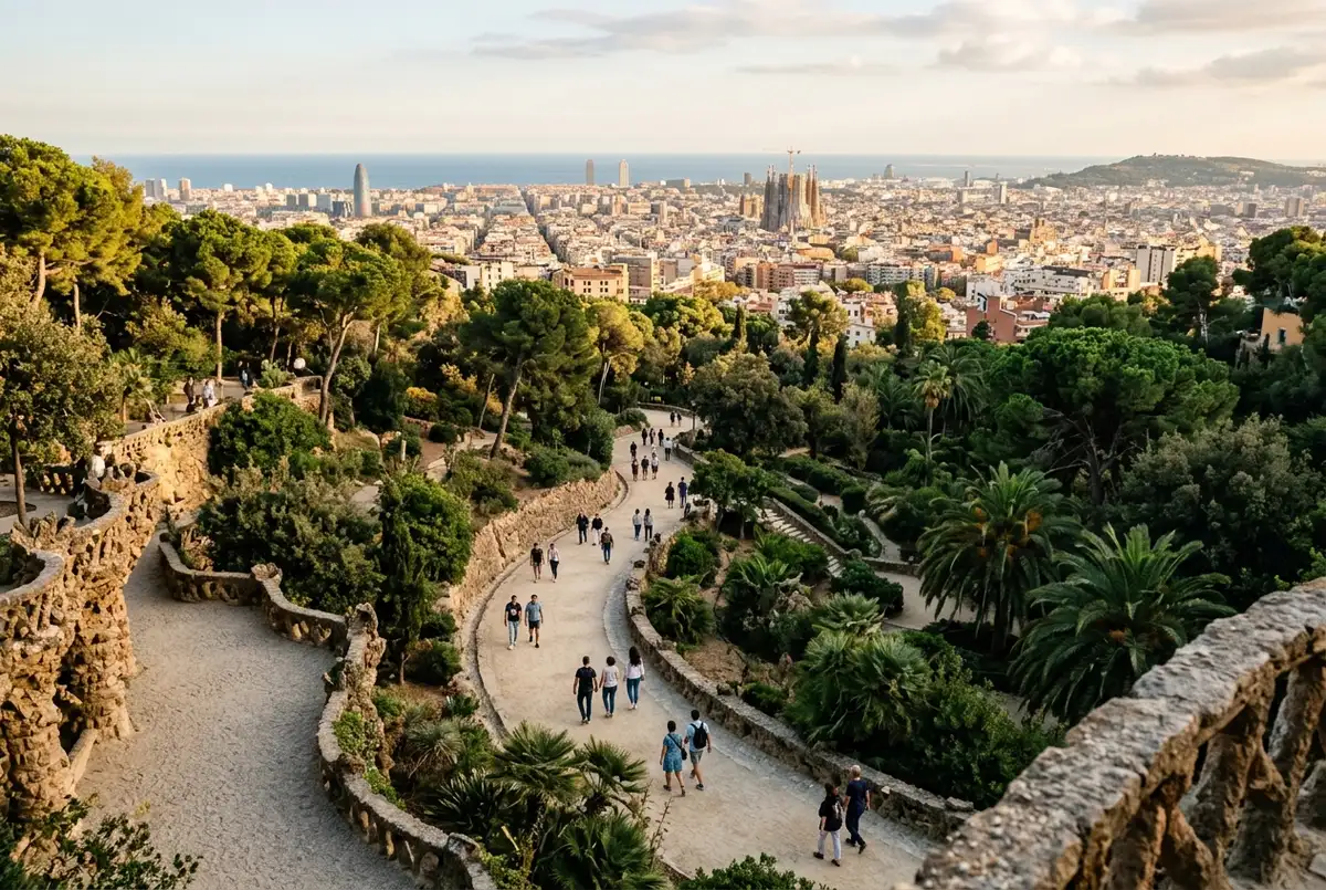 Overhead view of a path leading from Park Guell's free wooded gardens toward a gated entrance into the ticketed mosaic terraces