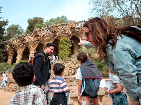 Çocuk turunda Park Güell'deki dalgalı mozaik bankı keşfeden aile