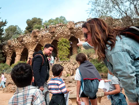 Gezin verkent de golvende mozaïekbank bij Park Güell tijdens de kindertour