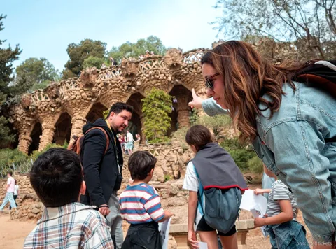 Famille découvrant le banc en mosaïque en forme de vague au Park Güell lors de la visite enfants